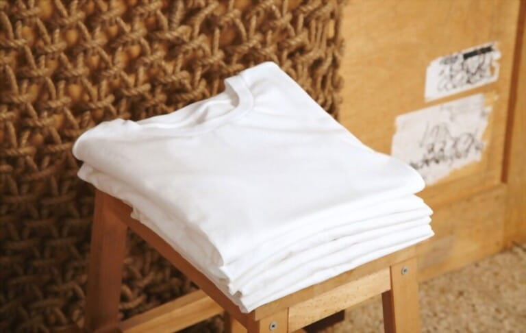 Various white folded basic cotton t-shirts presented in rustic interiors