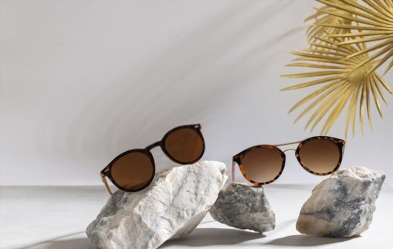 Sunglasses sale concept. Trendy sunglasses on a light background with golden palm leaves. Trendy Fashion summer accessories. Side view, copy space for text. Optic store. Vacation, travel concept Sunglasses sale concept. Trendy sunglasses on a light background with golden palm leaves. Trendy Fashion summer accessories. Side view, copy space for text. Optic store. Vacation, travel concept