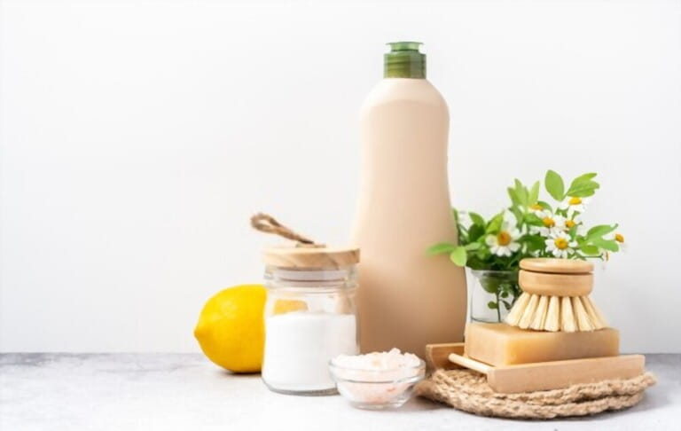 Eco friendly natural cleaners, jar with baking soda, dish brush, lemon, flowers, soap on white background. Organic ingredients for homemade cleaning with mock up bottle. Zero waste concept, copy space