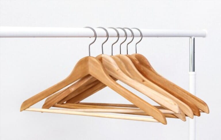 Metal rack with wooden clothes hangers on white background