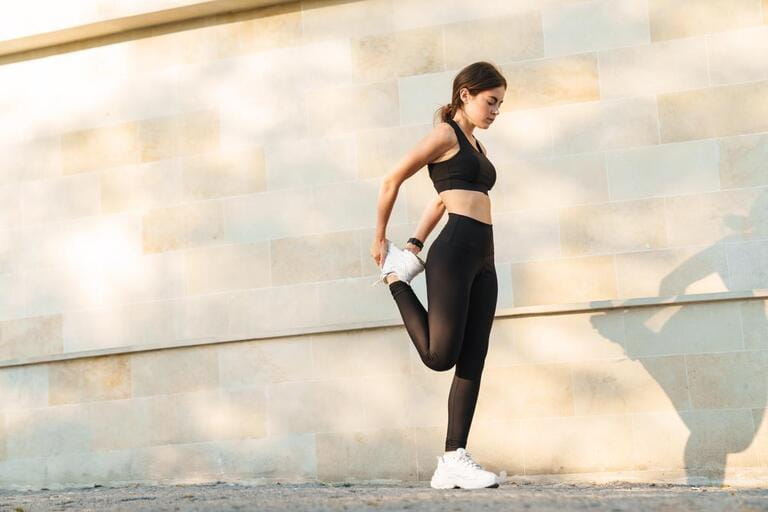 Image of caucasian athletic sportswoman doing exercise while working out at city street