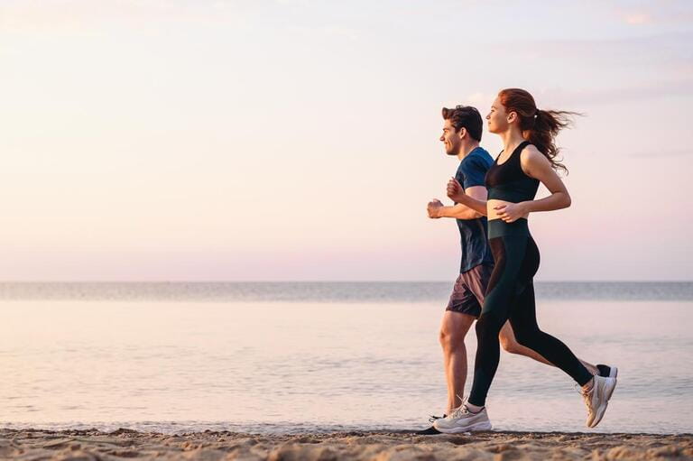 Full body profile couple young two friends strong sporty sportswoman sportsman woman man 20s in sport clothes warm up training run on sand sea ocean beach outdoor jog on seaside in summer day morning