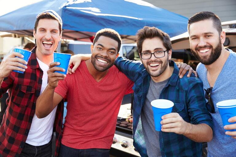 Group Of Male Sports Fans Tailgating In Stadium Car Park